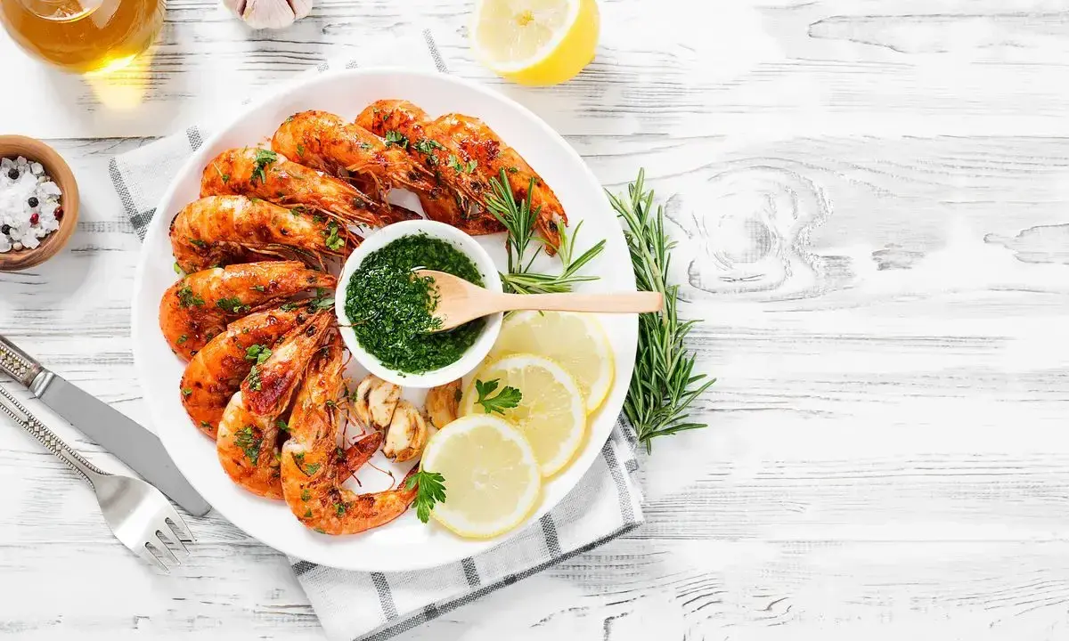 Gamberoni succulenti cotti nella friggitrice ad aria, serviti con salsa verde, limone e rosmarino.