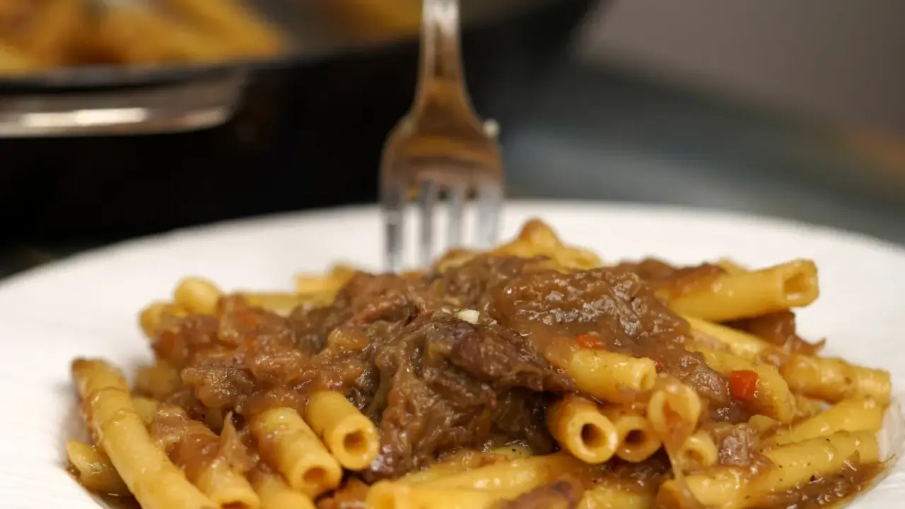 Un piatto invitante di ziti alla genovese, con la pasta condita da un ricco ragù di carne e cipolle.
