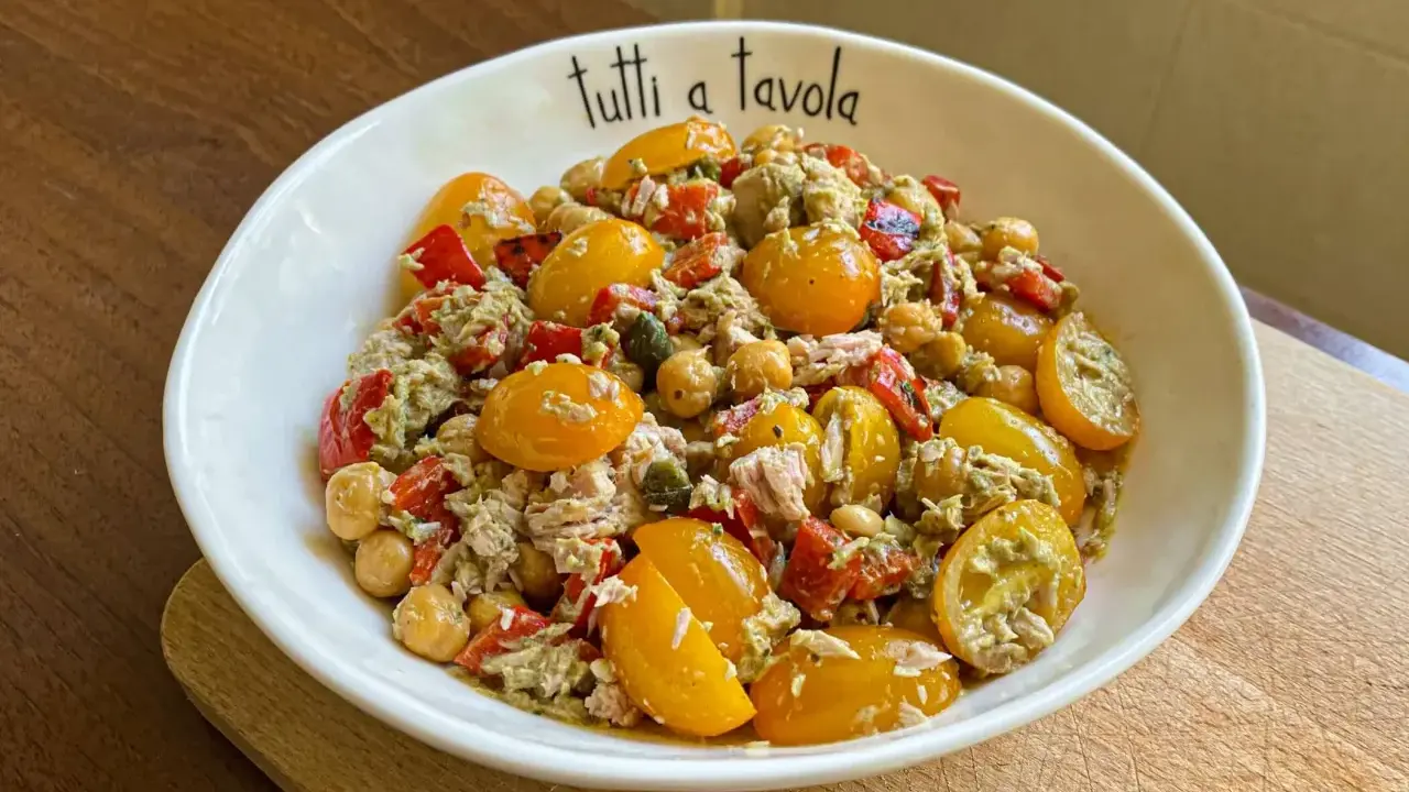 Insalata di tonno con pomodorini gialli, ceci e peperoni rossi, condita con un pesto leggero. Perfetta per un pasto fresco e gustoso.