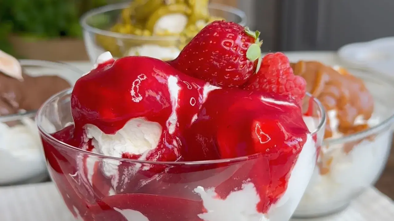Coppetta di gelato alla fragola, con fragole fresche e salsa rossa. Scopri come fare il gelato senza gelatiera per un dessert delizioso.