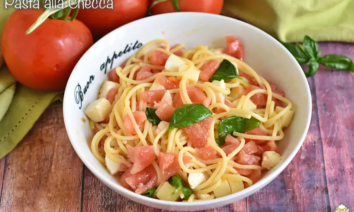 Un piatto di pasta alla checca con pomodori freschi, mozzarella e basilico, pronto per essere gustato.