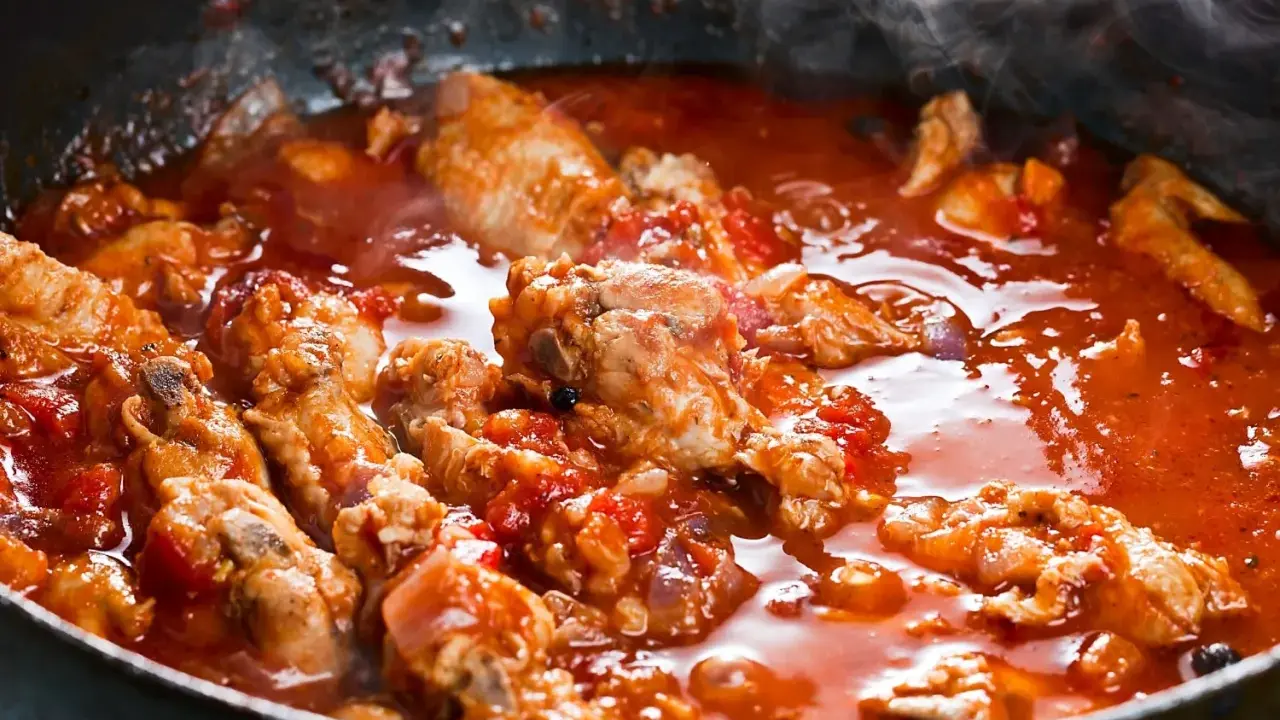 Carne alla pizzaiola morbida che sobbolle in padella, con pomodoro e profumi invitanti.