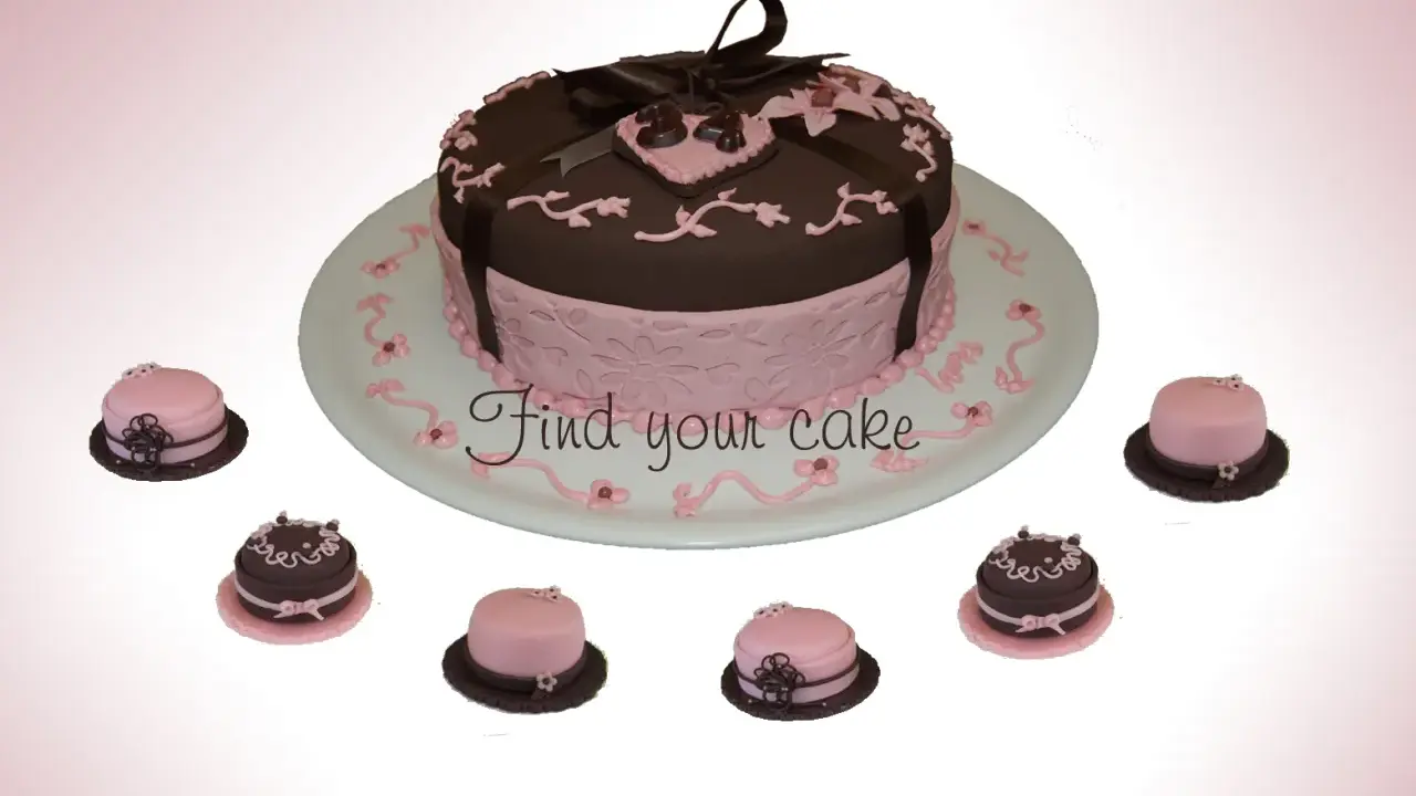 Torta centrale marrone e rosa con decorazioni in pasta di zucchero, circondata da mini-torte.