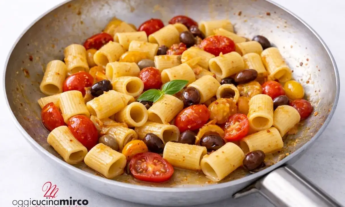 Rigatoni con pomodorini gialli, olive nere e basilico fresco, un piatto semplice e gustoso.