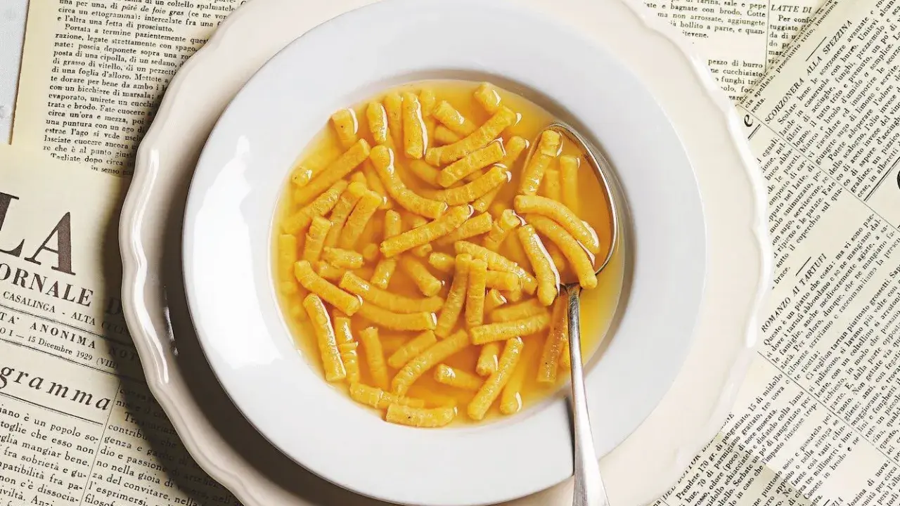 Passatelli in brodo, un classico della ricetta italiana, serviti in un piatto bianco su vecchie pagine di giornale.