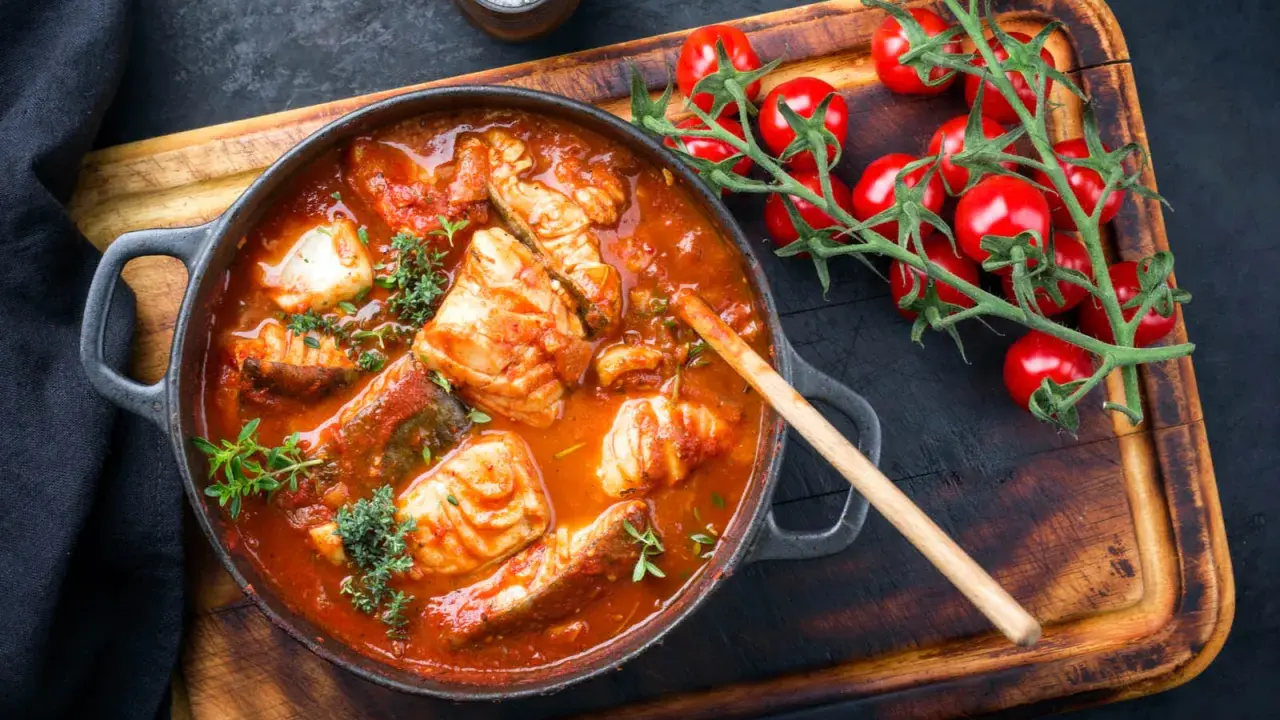 Un invitante guazzetto di pesce in umido, con pomodorini freschi e erbe aromatiche, pronto per essere gustato.