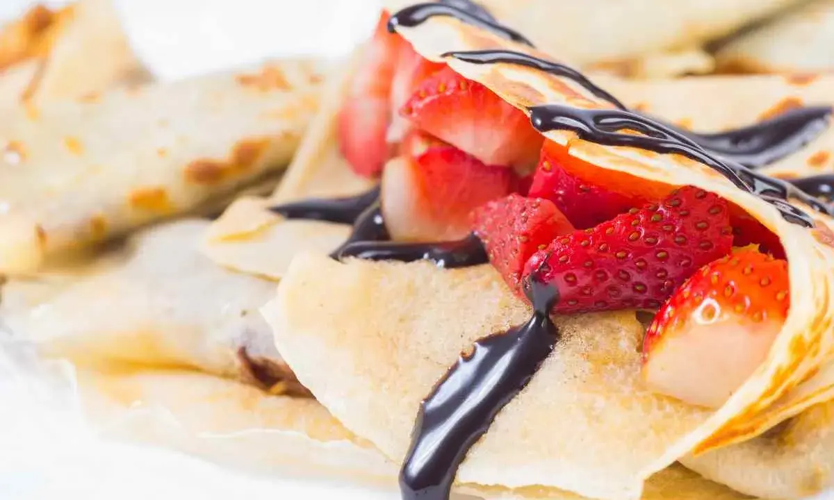 Deliziose crepes senza burro, ripiene di fragole fresche e ricoperte da una cascata di cioccolato fondente.