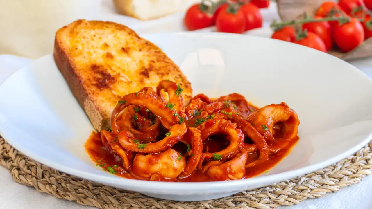 Moscardini in umido succulenti, serviti con pane tostato e pomodorini freschi. Un piatto che sa di mare e tradizione.