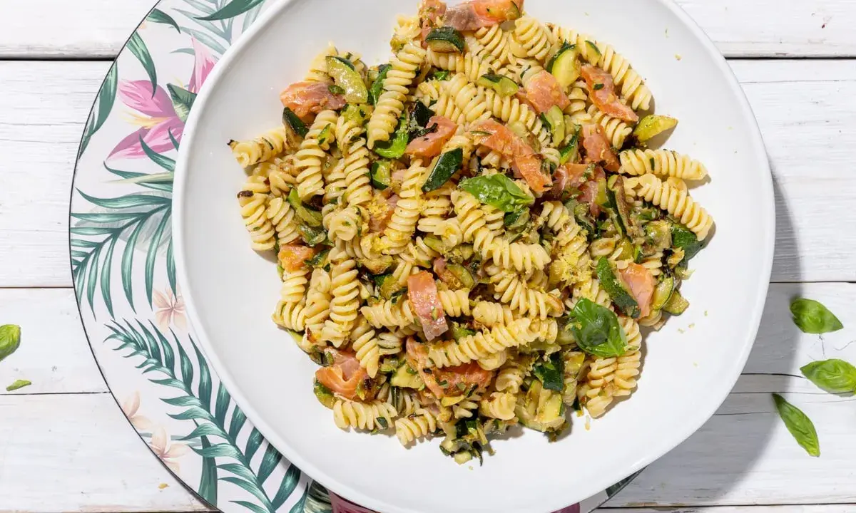Fusilli con salmone e zucchine, un piatto fresco e colorato, guarnito con basilico.