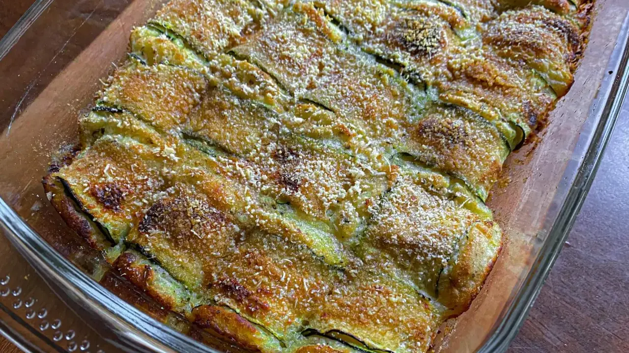 Involtini di zucchine grigliate al forno, dorati e croccanti, in una pirofila di vetro.