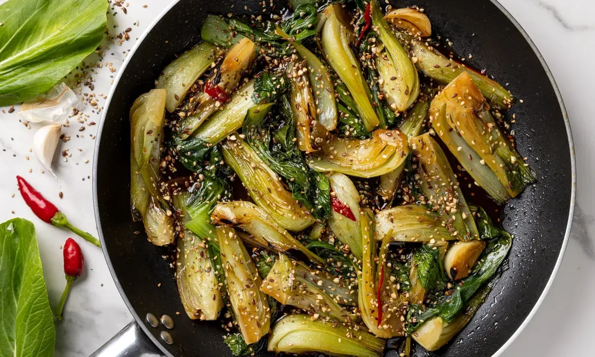 Verdure in padella, bok choy saltato con aglio, peperoncino e semi di sesamo, un piatto saporito e colorato.