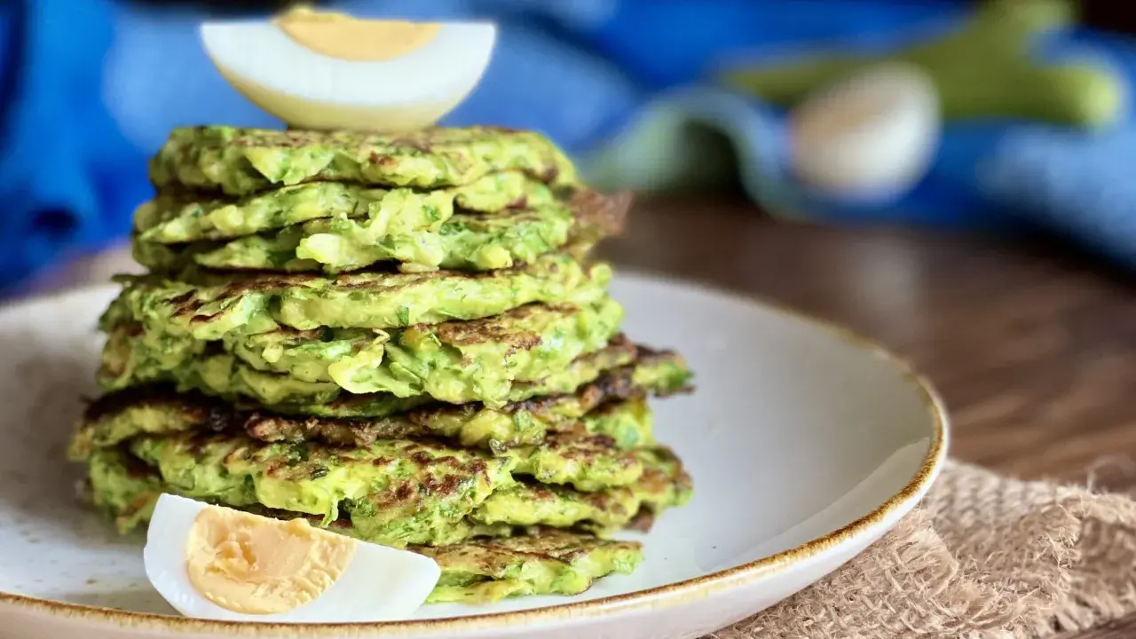 Pila di rosti di zucchine dorati, guarnita con spicchi di uovo sodo. Un piatto leggero e gustoso, perfetto per ogni pasto.