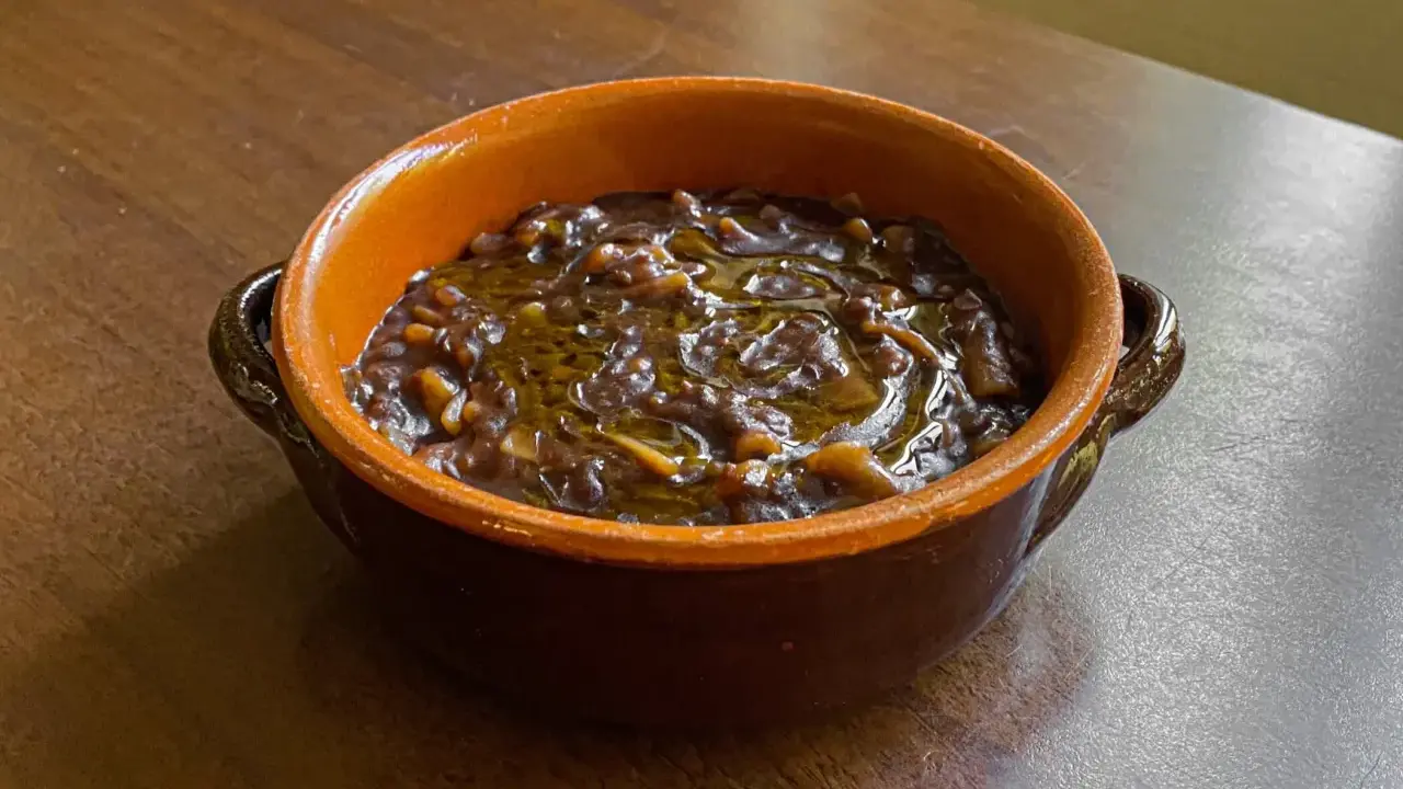 Una ciotola di terracotta con un saporito piatto di pasta e lenticchie, condito con olio d'oliva.