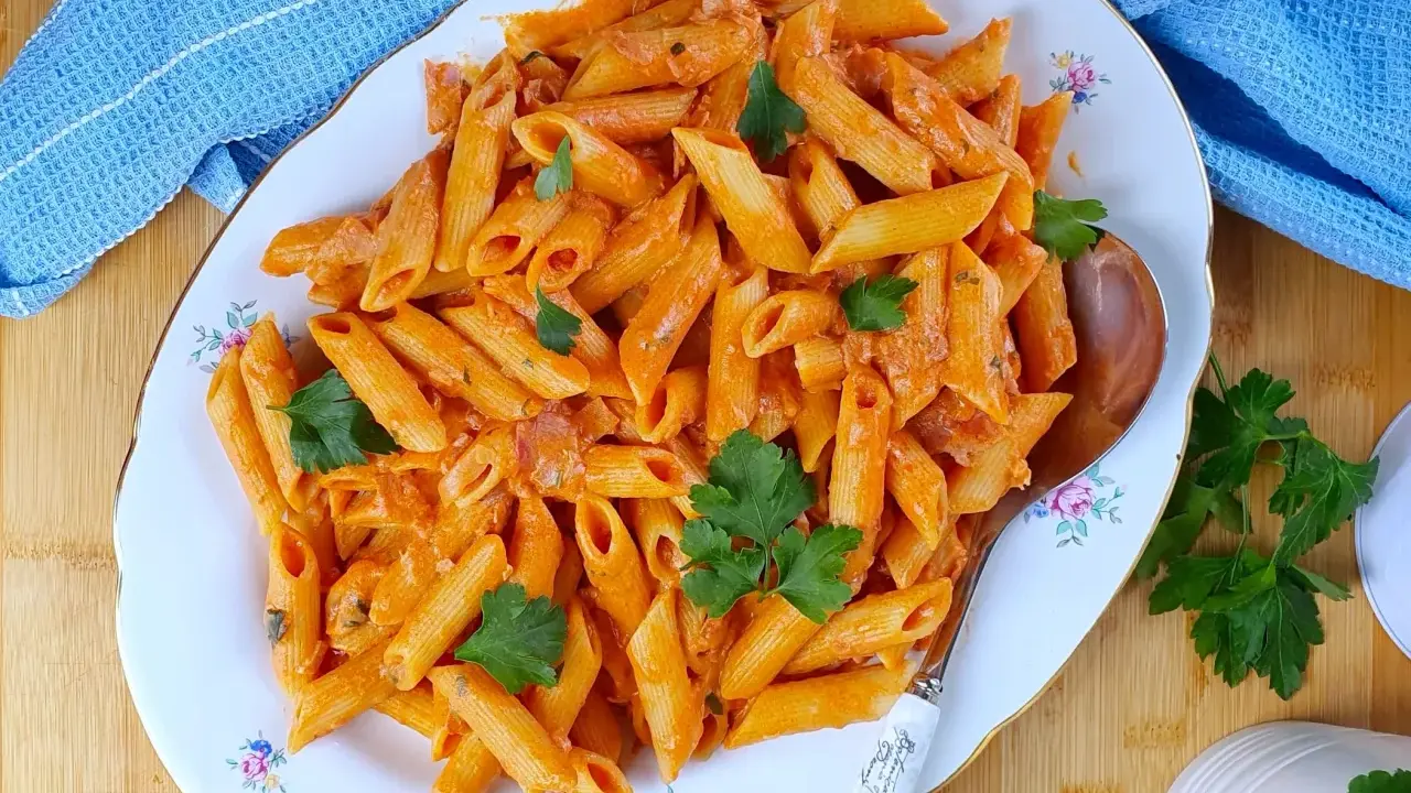 Penne al baffo cremose e saporite, guarnite con prezzemolo fresco, servite su un piatto elegante.