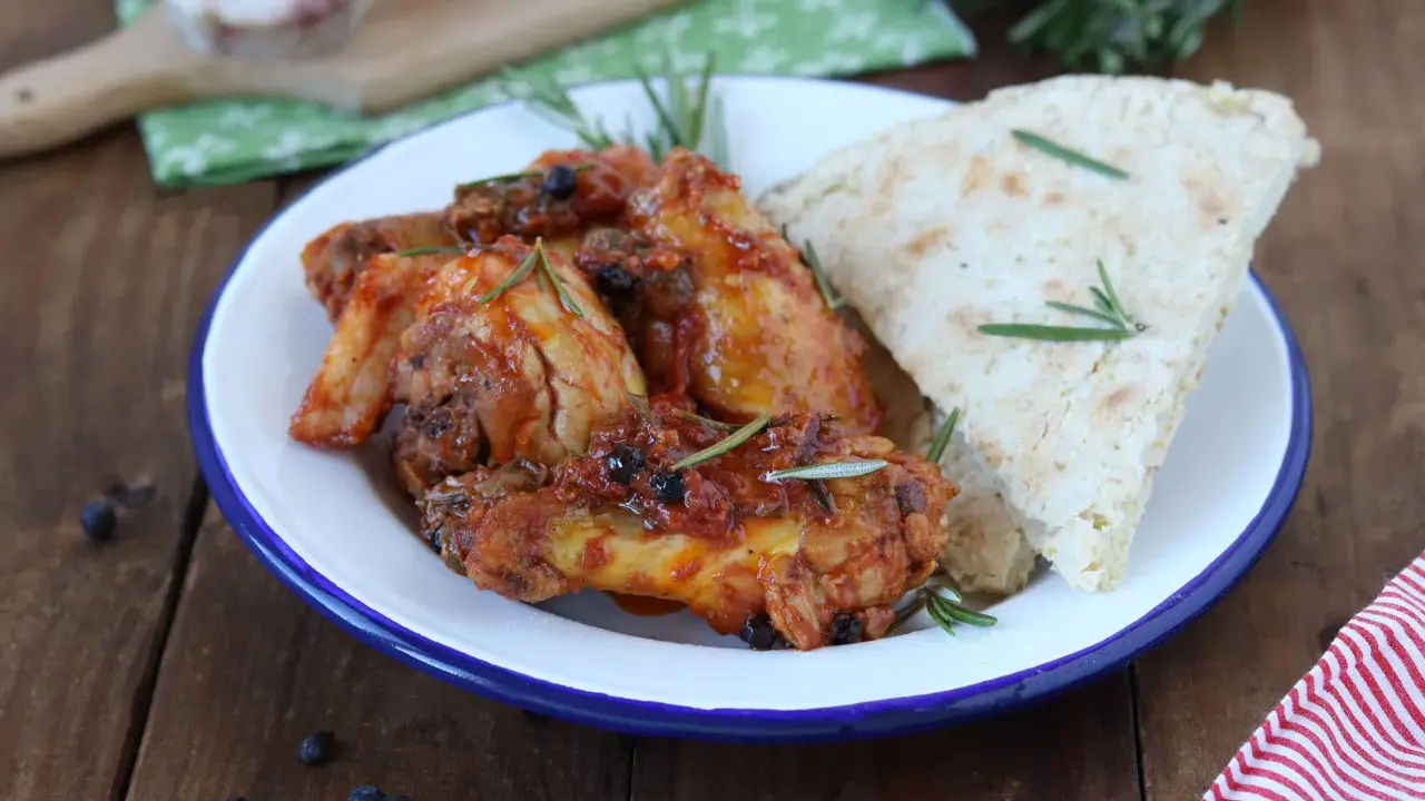 Piatto di friccò di pollo succulento con rosmarino e pane rustico su un piatto smaltato.