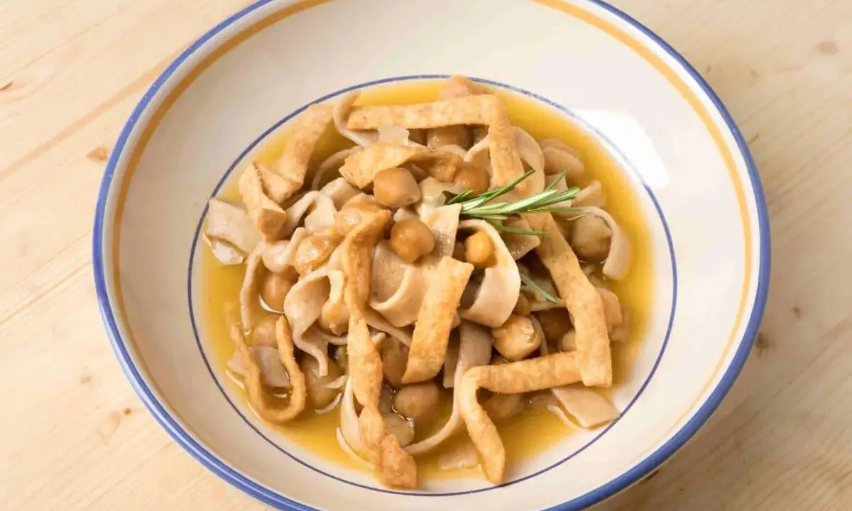 Piatto di ciceri e tria, pasta fresca con ceci e croccanti straccetti fritti, guarnito con rosmarino.