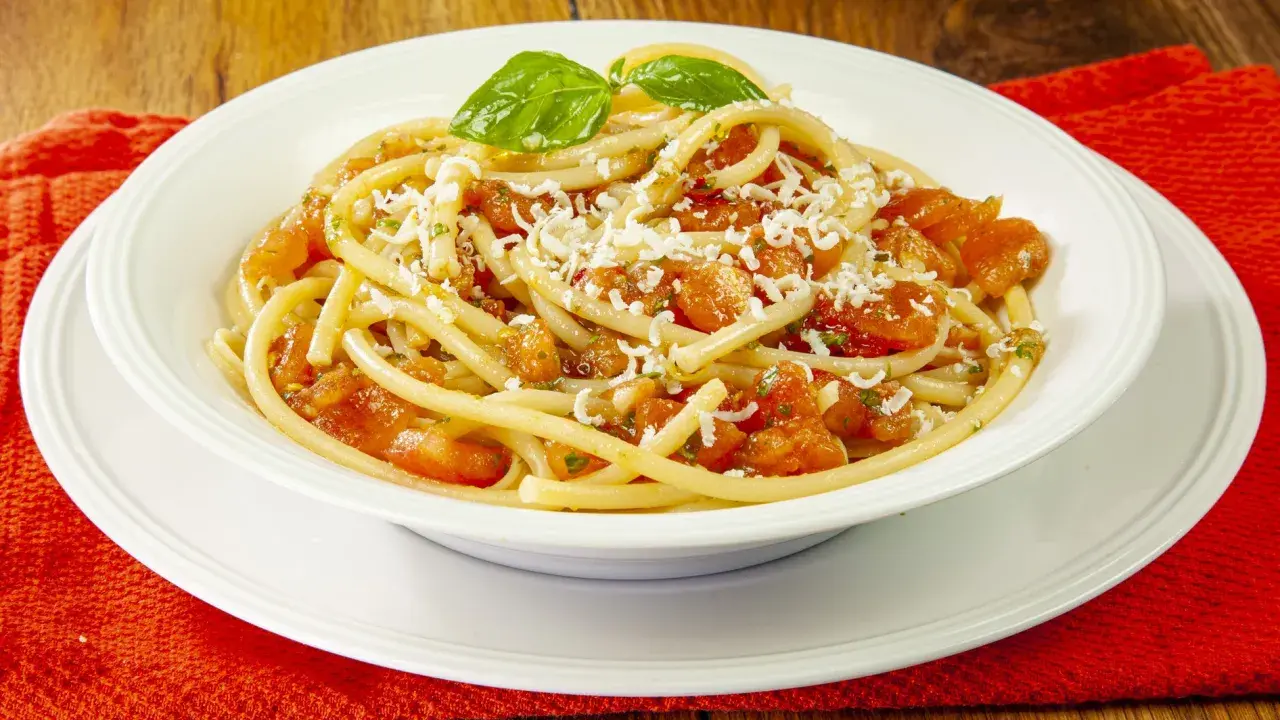 Un piatto di pasta alla carrettiera fumante, con pomodoro fresco, basilico e abbondante formaggio grattugiato.