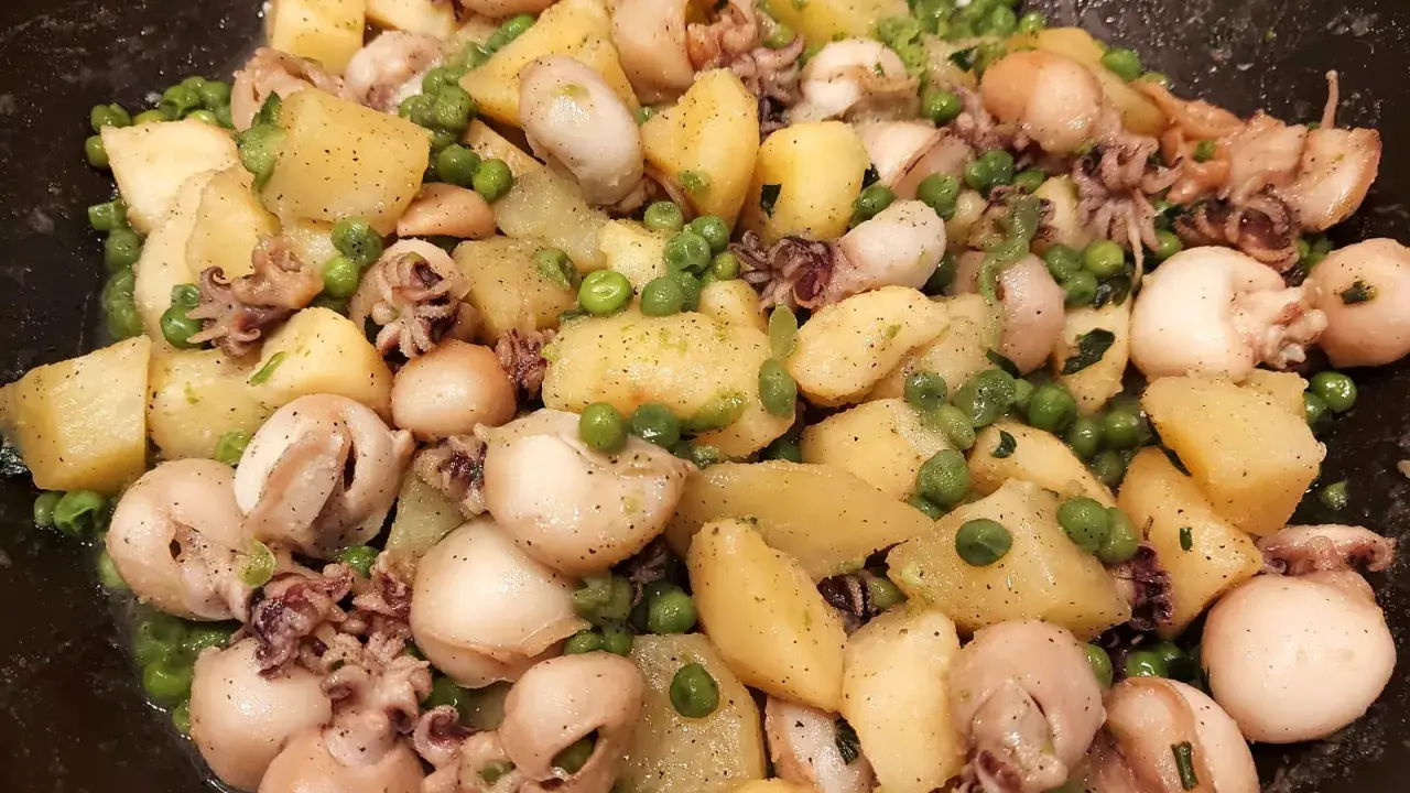 Un gustoso piatto di seppie e patate, con piselli verdi sparsi, condito con erbe aromatiche.