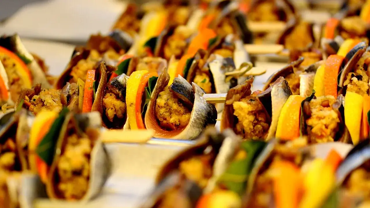 Sarde a beccafico su spiedini, con fette d'arancia e limone, un antipasto siciliano colorato e invitante.