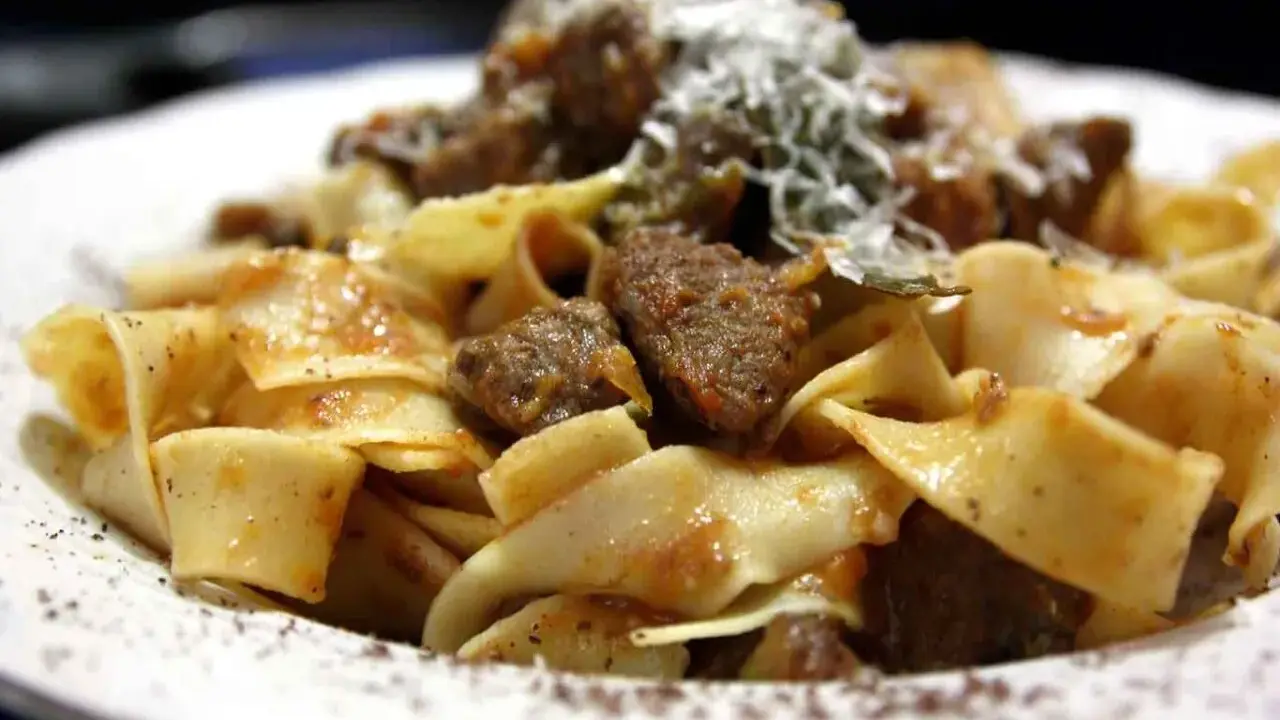 Pappardelle al cinghiale, un piatto ricco e saporito con pasta fresca e ragù di cinghiale, spolverato di parmigiano.