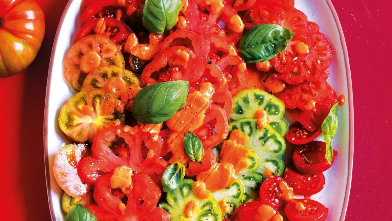 Un'insalata di pomodori colorati, affettati e conditi con erbe aromatiche fresche.