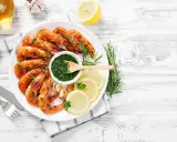 Gamberoni succulenti cotti nella friggitrice ad aria, serviti con salsa verde, limone e rosmarino.
