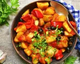 Patate e peperoni in padella, un piatto saporito con olive nere e prezzemolo fresco.