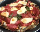 Parmigiana di alici in teglia, con pomodoro, mozzarella filante e basilico. Un piatto saporito e invitante.