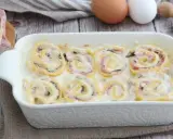 Rotolini di pasta con prosciutto e formaggio, cotti in una cremosa besciamella, sembrano piccoli nidi di rondine pronti per essere gustati.