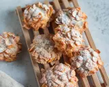 Deliziose rose del deserto, dolcetti croccanti ricoperti di fiocchi di mais e spolverati di zucchero a velo, su un tagliere di legno.