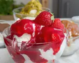 Coppetta di gelato alla fragola, con fragole fresche e salsa rossa. Scopri come fare il gelato senza gelatiera per un dessert delizioso.