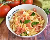 Un piatto di pasta alla checca con pomodori freschi, mozzarella e basilico, pronto per essere gustato.