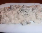 Un cremoso risotto con salsiccia, servito su un piatto bianco.