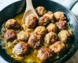 Polpette di carne morbide in padella, dorate e succulente, cuociono in un sughetto saporito con cipolle.