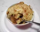 Un delizioso crumble di mele appena sfornato, con la sua crosta dorata e il ripieno succoso, pronto per essere gustato con un cucchiaino.