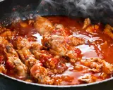 Carne alla pizzaiola morbida che sobbolle in padella, con pomodoro e profumi invitanti.