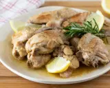 Succulento pollo al limone, dorato e profumato, servito con spicchi di limone fresco e rosmarino su un piatto bianco.