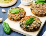 Hamburger di melanzane fatti in casa, guarniti con foglie di spinaci freschi, pronti per essere gustati.