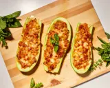Zucchine ripiene velocissime, dorate e filanti, su tagliere di legno con basilico fresco.