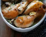 Cosce di pollo succulente, dorate e profumate al rosmarino e aglio, servite in una ciotola bianca.