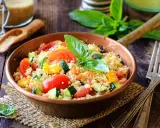 Un piatto colorato con cous cous, pomodori, zucchine e peperoni, perfetto per una ricetta cous cous originale e fresca.