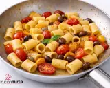 Rigatoni con pomodorini gialli, olive nere e basilico fresco, un piatto semplice e gustoso.