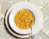 Passatelli in brodo, un classico della ricetta italiana, serviti in un piatto bianco su vecchie pagine di giornale.