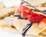 Deliziose crepes senza burro, ripiene di fragole fresche e ricoperte da una cascata di cioccolato fondente.