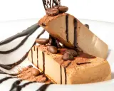 Due fette di semifreddo al caffè, decorate con cacao, chicchi di caffè e salsa al cioccolato, su un piatto bianco.
