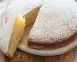 Una soffice torta senza uova, cosparsa di zucchero a velo, con una fetta tagliata che ne mostra l'interno chiaro e profumato.