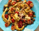 Calamari gratinati al forno su piatto blu, con pomodorini e olive. Croccanti e saporiti, un piatto che profuma di mare.