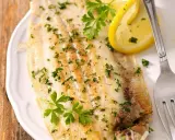 Sogliola al forno, dorata e profumata, guarnita con prezzemolo fresco e spicchi di limone. Un piatto leggero e saporito.
