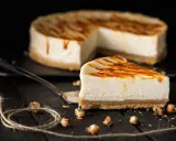 Una fetta di cheesecake senza gelatina, con colatura di caramello, su un piatto scuro.