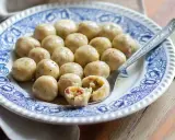 Gnocchi di pane su piatto decorato, uno spezzato rivela un ripieno saporito.